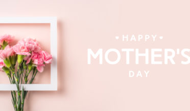 event design concept - top view of a bunch of pink carnation with white photo frame and greeting word on pink background for mothers day event with copy space for mock up